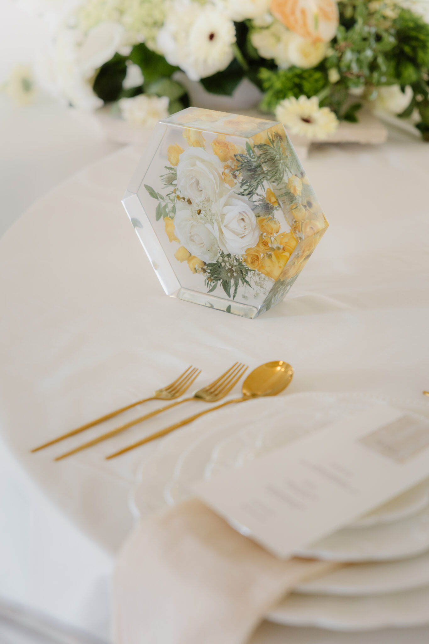 Sechseckiger Acrylglas-Block mit konservierten weißen und gelben Hochzeitsblumen als Tischdekoration