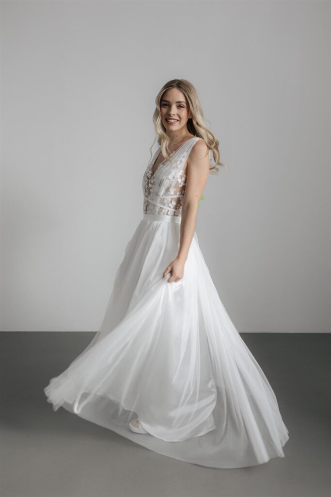 Braut im weißen Tüllkleid mit Spitzen-Oberteil dreht sich lächelnd – Hochzeitsinspiration – Flomory Blog