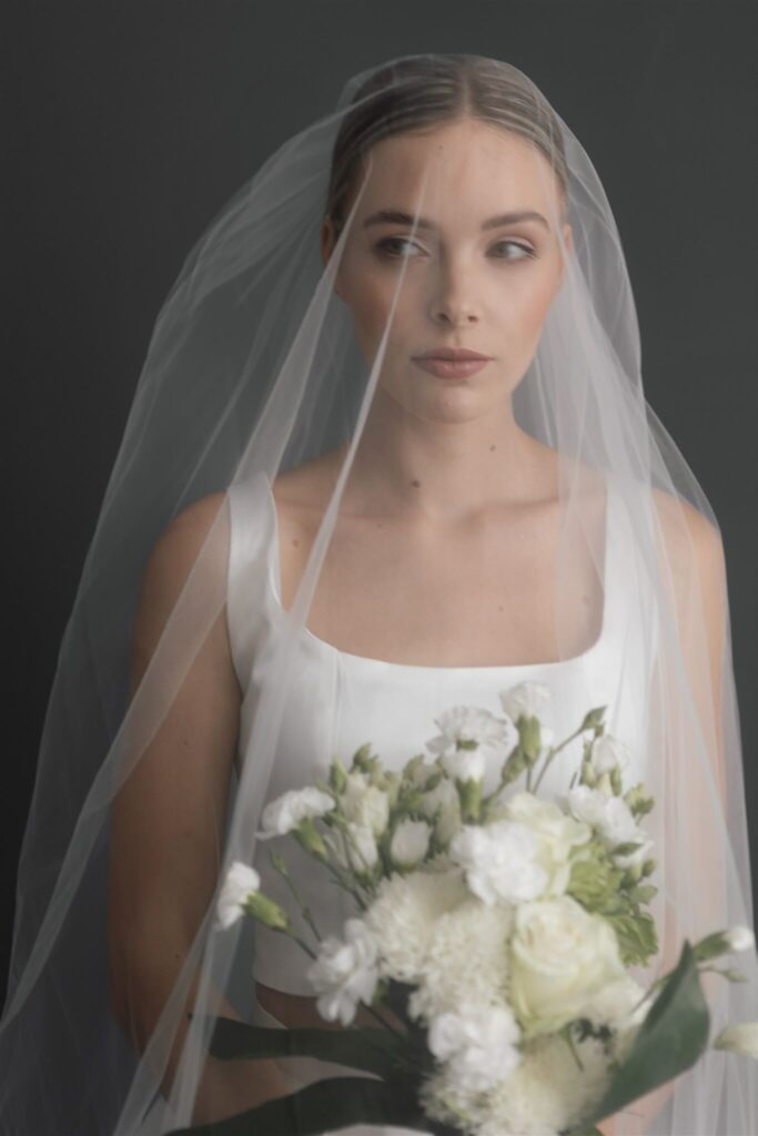 Braut mit Schleier und weißem Brautstrauß aus Rosen und Lisianthus – Hochzeitsportrait – Flomory Blog